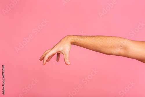Caucasian man hand hanging something blank isolated on a pink background. Close-up.