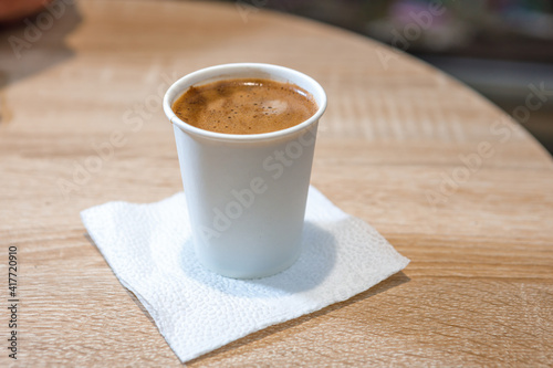 Freshly brewed coffee in a paper cup on a paper napkin is on the table. Ecological tableware.