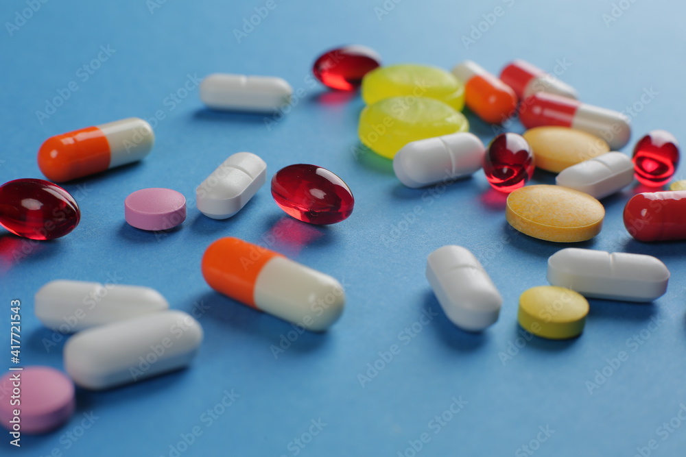 Multicolored pills of various shapes on a blue background Multicolored pills of various shapes on a blue background