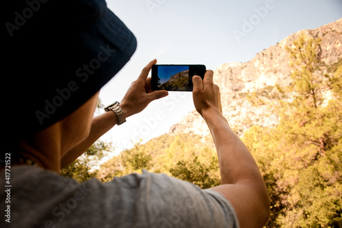 close-up of male hands with smartphone with which he make photo of mountain