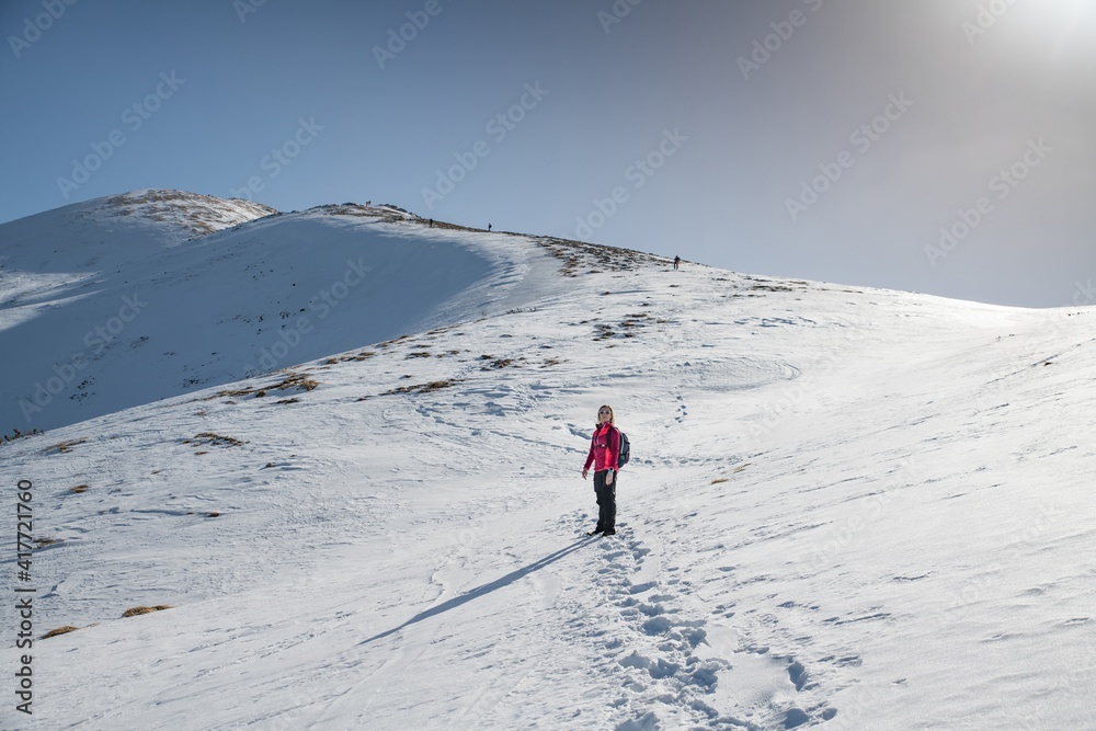 Woman hiker on the mountain winter trail. Beautiful snowy day