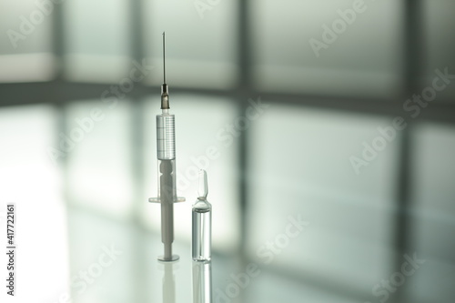 Medicine vial and syringe on glass table