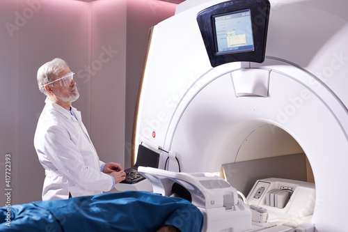 Medical technical assistant performing radiological scan of patient with magnetic resonance tomography MRI  modern technologies in medicine