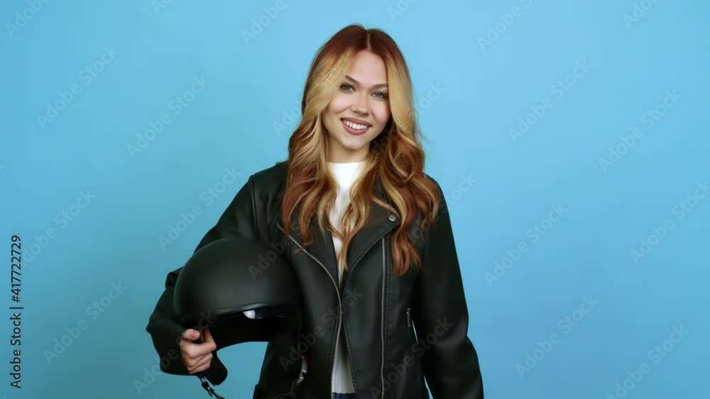 Teenager woman holding a motorcycle helmet presenting and inviting to come with hand over isolated background