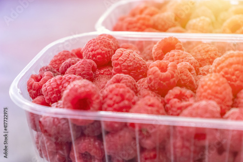 Pile of raw beautiful raspberries at plastic container. texture, backdrop. fresh dessert berries