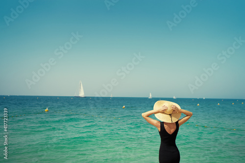 Lonely and calm. Vacation on the sea. Young woman in hat walking  on beach. © luengo_ua