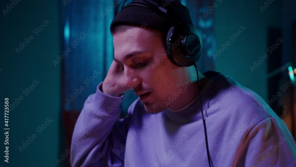 Night club, nightlife concept. DJ man hands hold headphones and mixing remote. Neon light, young musician streaming set in cafe Night club, nightlife concept. DJ man hands hold headphones and mixing remote. Neon light, young musician streaming set in cafe