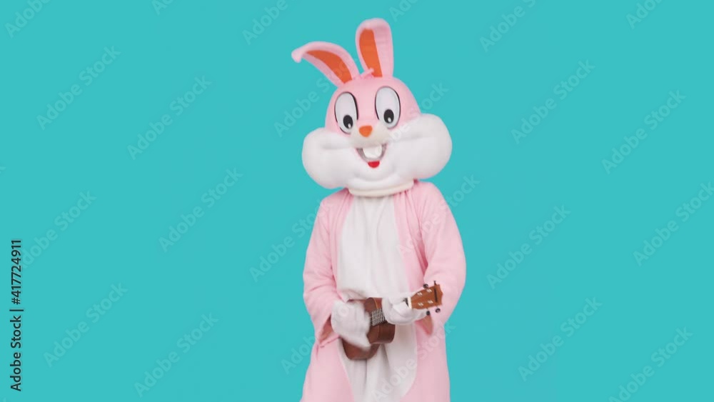 Funny musician kid boy or girl guitarist plays music by ukulele or Hawaiian guitar, dancing having fun, celebrates Happy easter Funny musician kid boy or girl guitarist plays music by ukulele or Hawaiian guitar, dancing having fun, celebrates Happy easter