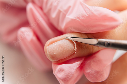 Manicure process. Cutting the cuticles on the finger with small scissors