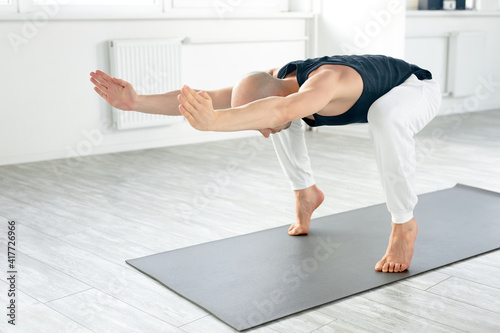 young yoga man doing various yoga poses indoors, stretching body for wellbeing and having muscular strong body