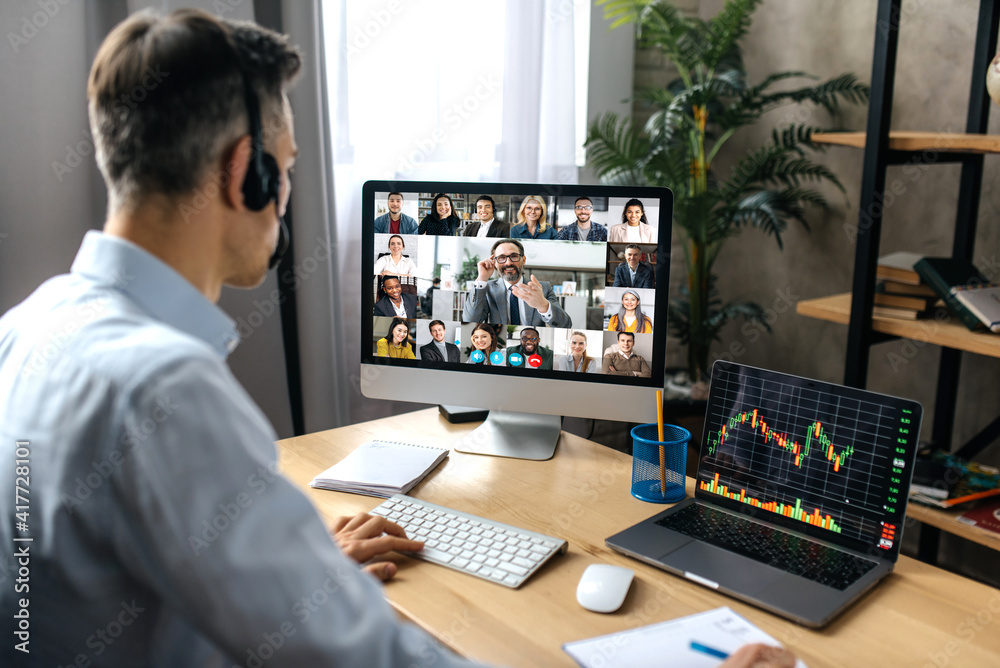 Virtual meeting, video call. Successful adult businessman have conversation with multiracial business colleagues by video call using a computer while sitting at his workplace