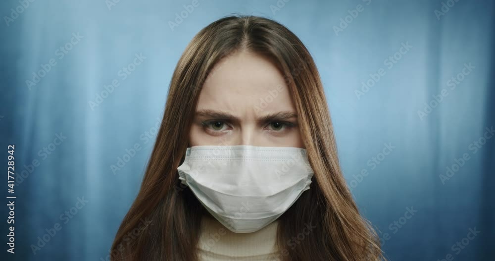 Covid-19, pandemic and quarantine concept. Close-up of sad teenager student woman wearing medical mask feeling lonely during coronavirus, standing against blue background Covid-19, pandemic and quarantine concept. Close-up of sad teenager student woman wearing medical mask feeling lonely during coronavirus, standing against blue background