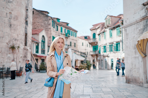 Travel and active lifestyle concept. Young traveller woman walking on old town holding tourist map.