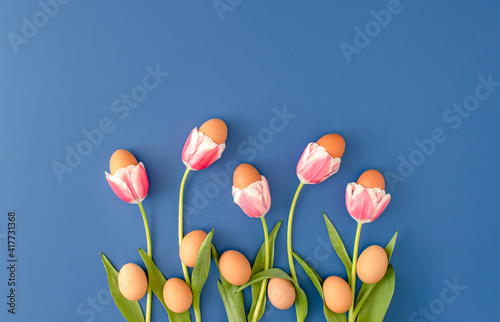 Creative Easter layout made with pink tulip and brown natural eggs against deep blue background. Eggs hatch from flowers. Minimal Easter holiday concept. #417731368