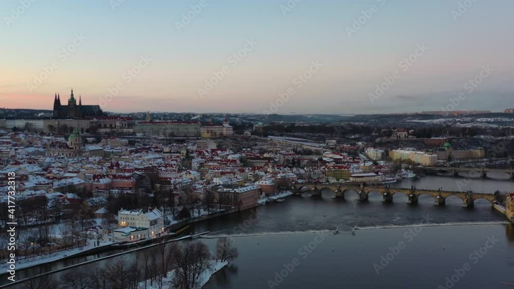 Snow capped Prague, Czech Republic. Aerial view, Charles bridge, castle, Vltava river, St. Virus cathedral and sunset skyline on cold winter evening, drone shot Snow capped Prague, Czech Republic. Aerial view, Charles bridge, castle, Vltava river, St. Virus cathedral and sunset skyline on cold winter evening, drone shot