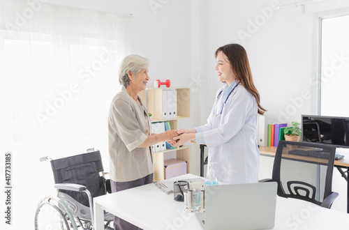 Asian doctor talk with old female patient about disease symptom, they holding hand together, elderly health check up, happiness hospital, hand in hand