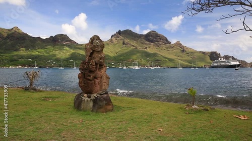 Nuku Hiva, Marquesas Islands. Stone Tiki sculpture and sea wave. photo