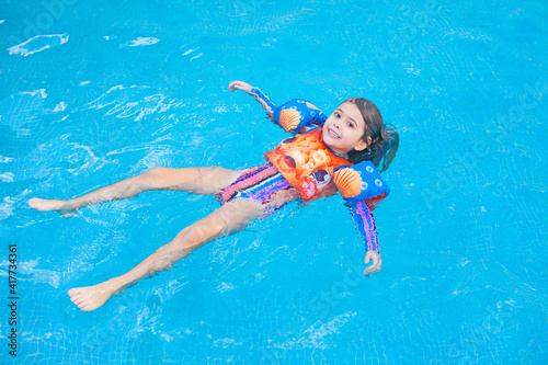 Kind mit Schwimmflügel und Schwimmweste im Schwimmbad