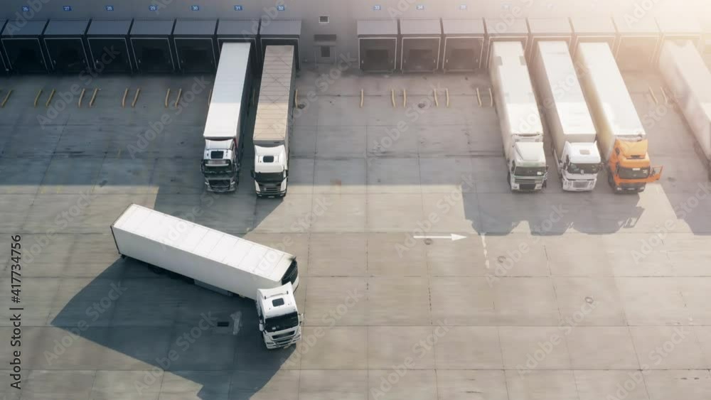 Semi truck with cargo trailer maneuvers along a parking lot of a