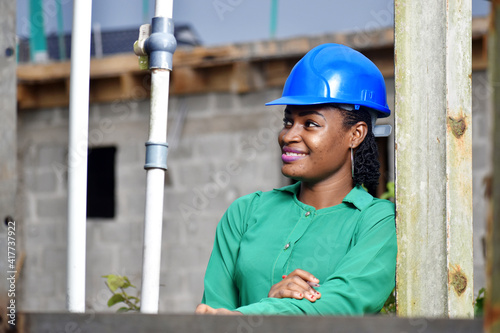 An attractive African Nigerian female construction and architectural engineer with blue safety helmet 