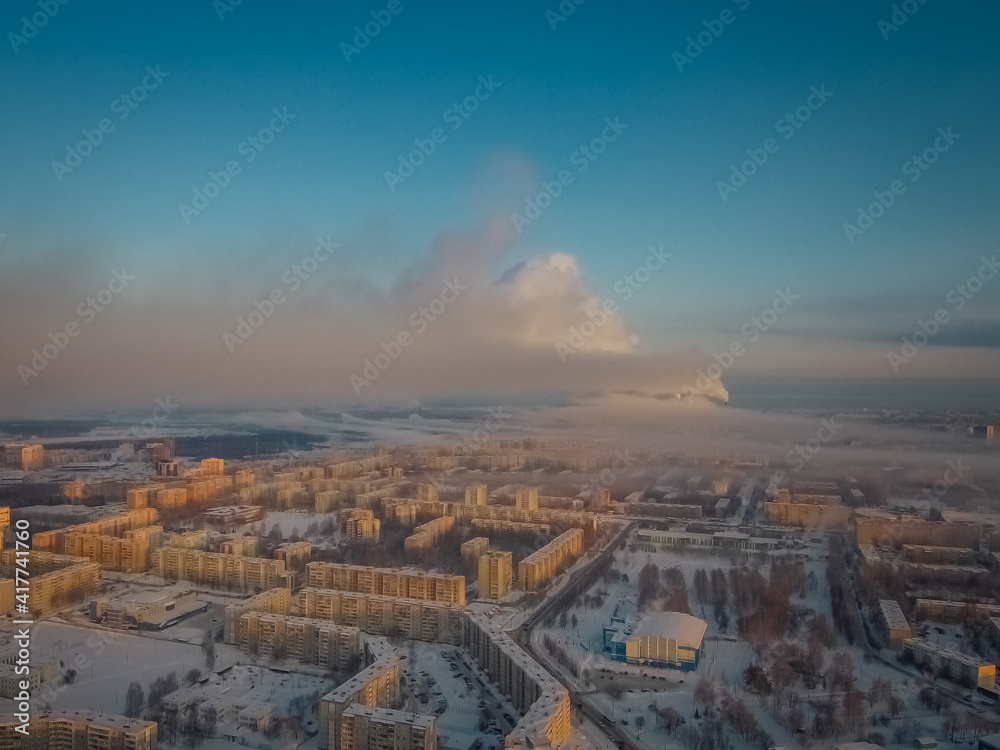 smoke from a working thermal power plant covers the blue sky in a frosty early morning