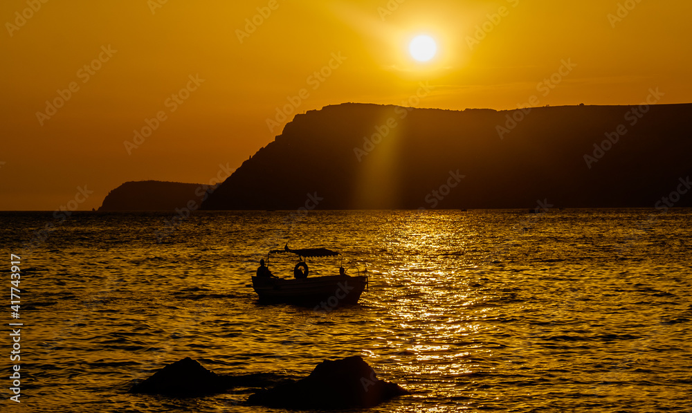 A pleasure boat in a quiet bay of the Black Sea in the light of the setting sun.