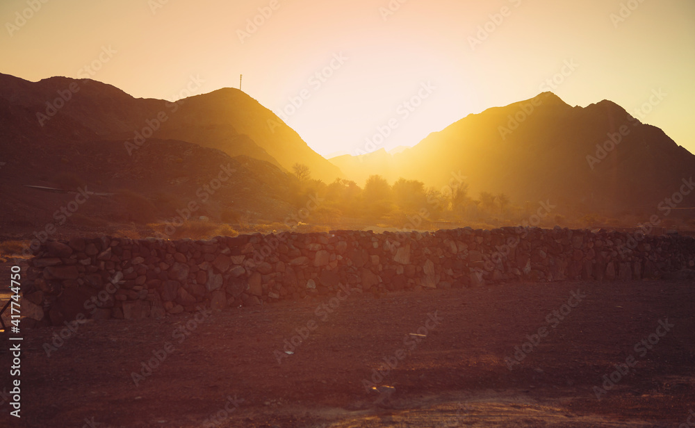 Golden sunset over the mountains in the wild desert. RAK, UAE Golden sunset over the mountains in the wild desert. RAK, UAE