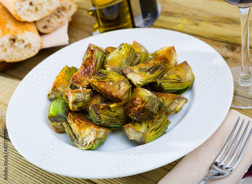 Photography Vegetarian appetizer of sauteed in oil artichokes served on white plate