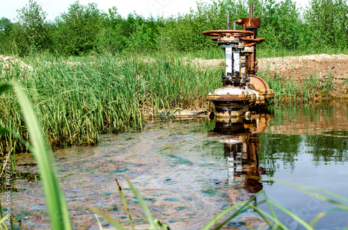 An old, rusty valve. Crude oil leaks into the water reservoir.