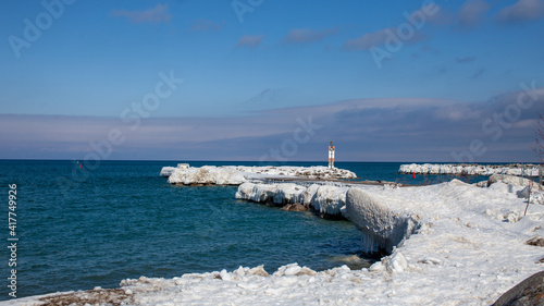 The frozen pier at the entrance of the Thornbury Yacht Club marina in the winter. Large ice sickles hang down from the shoreline after winter storms pack ice around the beach. photo