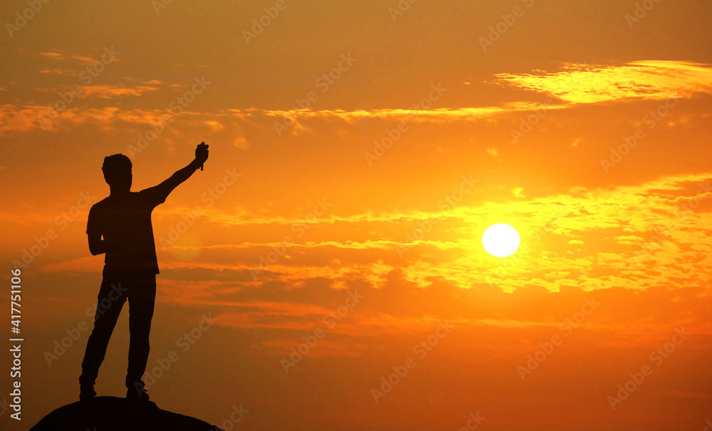 Fototapeta premium silhouette guy standing on the top to greet the sun set beauty multi color sky nature background