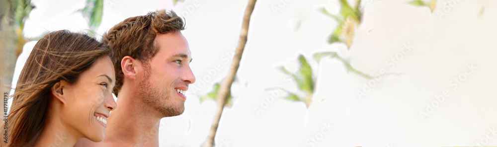 Happy smiling beautiful young models. Asian woman and caucasian man friends or couple with toothy perfect smiles profile portrait on outdoor white banner. Happy smiling beautiful young models. Asian woman and caucasian man friends or couple with toothy perfect smiles profile portrait on outdoor white banner.