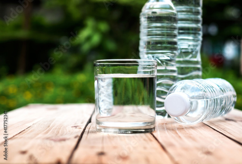 Clear water in a glass and a water bottle rests on a natural green natural wood floor.