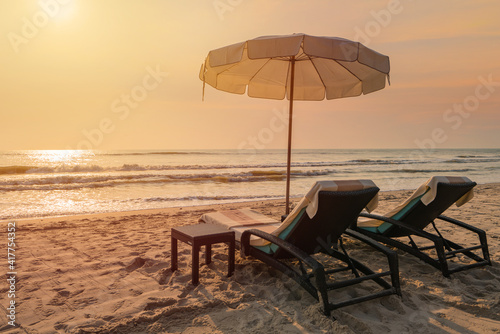 Sun umbrellas and chairs on tropical beach with sunset