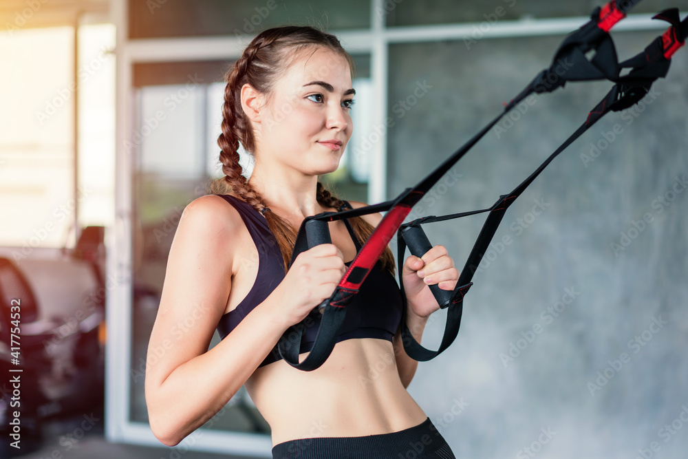 Athlete sporty woman doing exercise with fitness trx straps to strengthen his abdominal muscle in gym Athlete sporty woman doing exercise with fitness trx straps to strengthen his abdominal muscle in gym