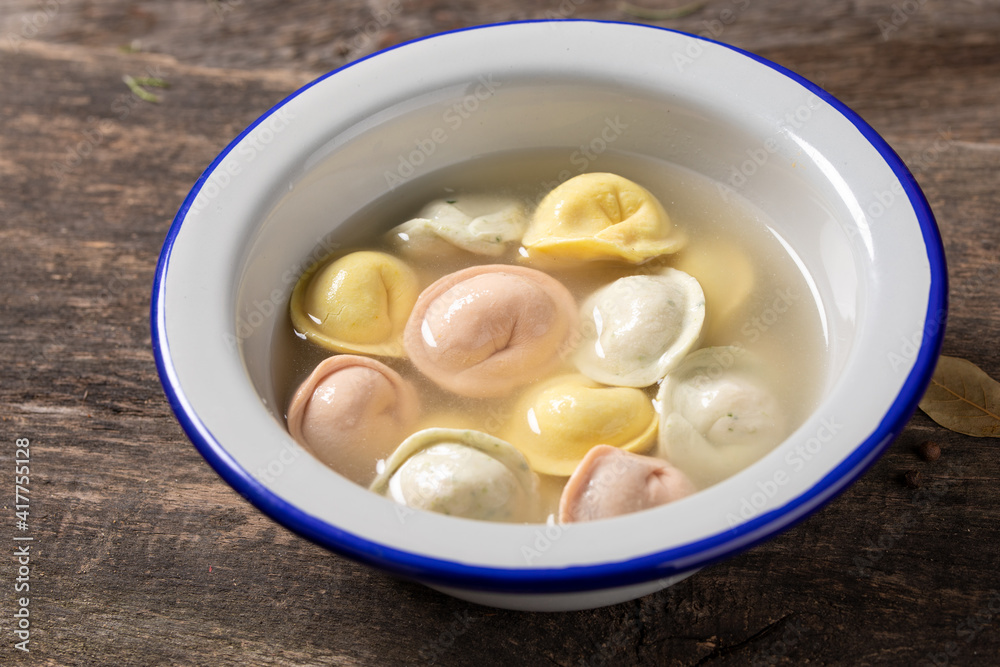 Traditional Russian dumplings made from multi-colored dough in broth. Dumplings on a wooden board in an enamel plate. Cooking concept. Traditional Russian dumplings made from multi-colored dough in broth. Dumplings on a wooden board in an enamel plate. Cooking concept.