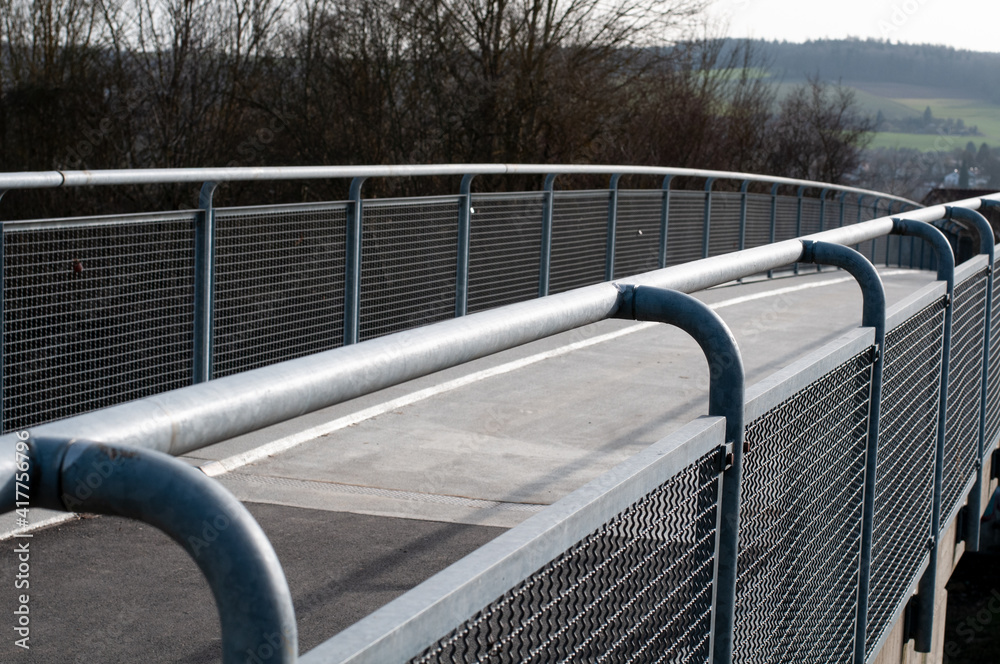 a concrete footbridge with a metal railing