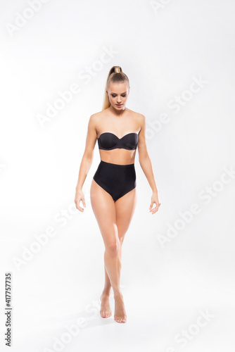 Young, fit and beautiful blond woman in white swimsuit isolated on white background. Healthcare, diet, sport and fitness. © Acronym
