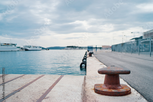 Iron pole for mooring of ships at pier. Landscape with sea wharf.