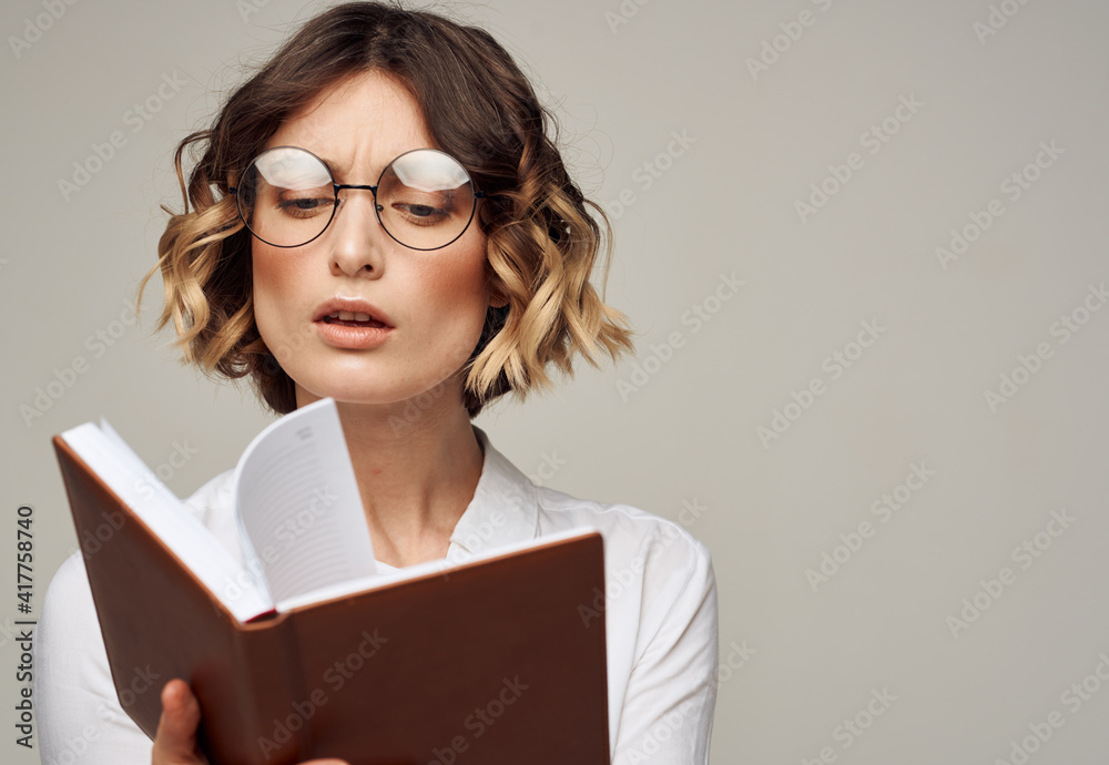 Literate woman with book in hands and in glasses white shirt education model