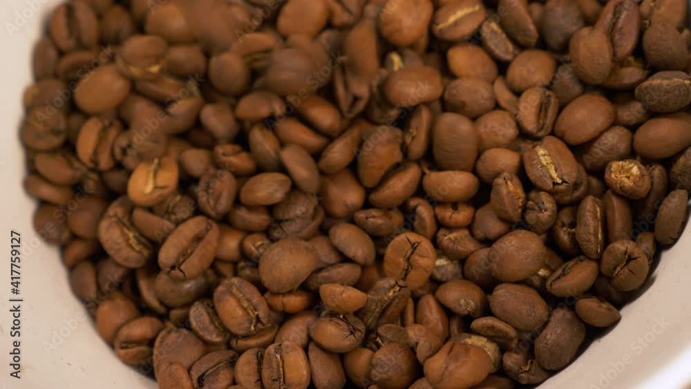 Pouring light roast coffee beans into a container, close up Pouring light roast coffee beans into a container, close up