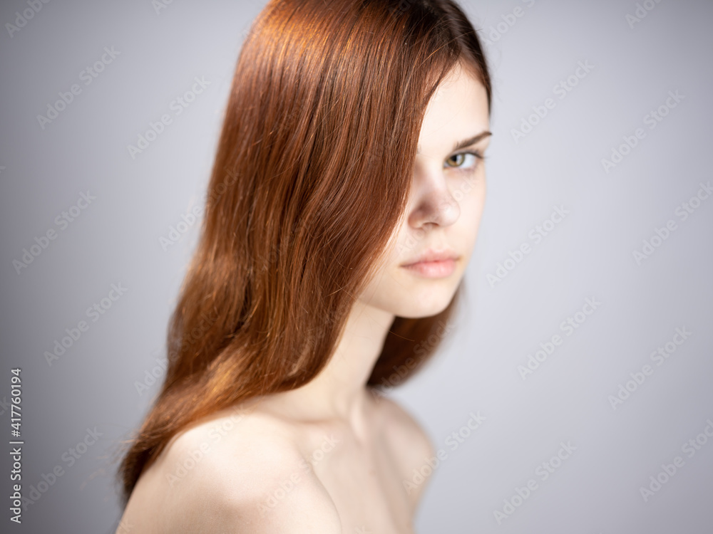 Portrait of a luxurious woman with red hair and bare shoulders on a gray background Portrait of a luxurious woman with red hair and bare shoulders on a gray background