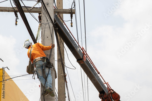 An electrician climbing a pole to install electrical equipment