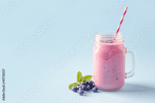 Mason jar of tasty berry smoothie on color background