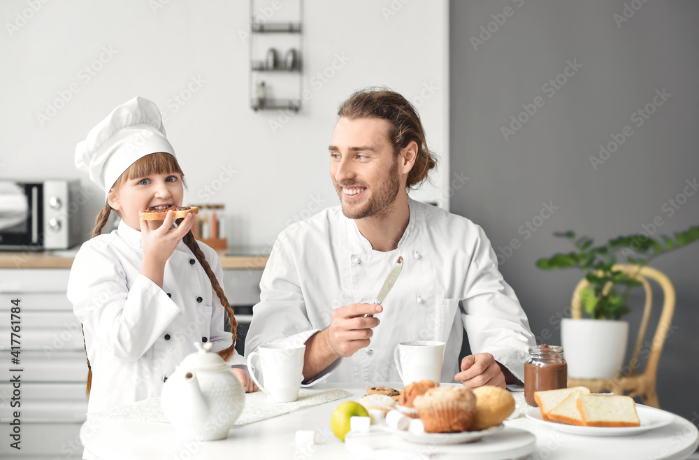 Happy father and daughter dressed as chefs making toasts at home Happy father and daughter dressed as chefs making toasts at home