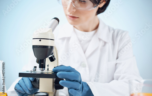 doctors in medical gloves look through a microscope on the table e laboratory chemical element vaccine