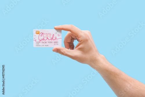 Hand with gift card on color background