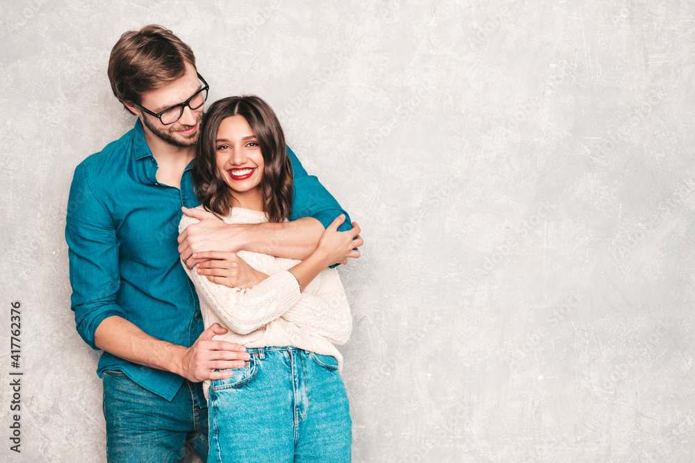 Smiling beautiful woman and her handsome boyfriend. Happy cheerful family having tender moments near grey wall in studio.Pure cheerful models hugging.Embracing each other