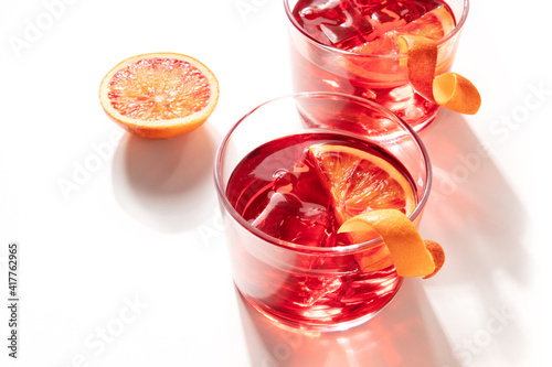 Negroni cocktails with blood oranges and ice on a white background, with shadows
