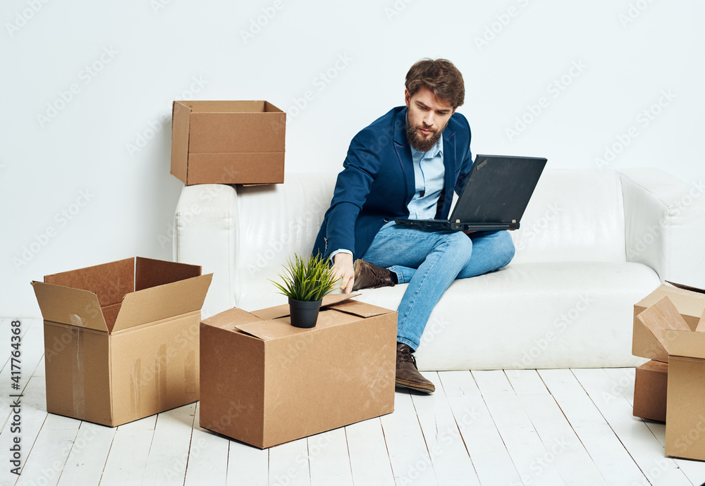 Business man sitting on the couch with laptop boxes with things unpacking office official Business man sitting on the couch with laptop boxes with things unpacking office official